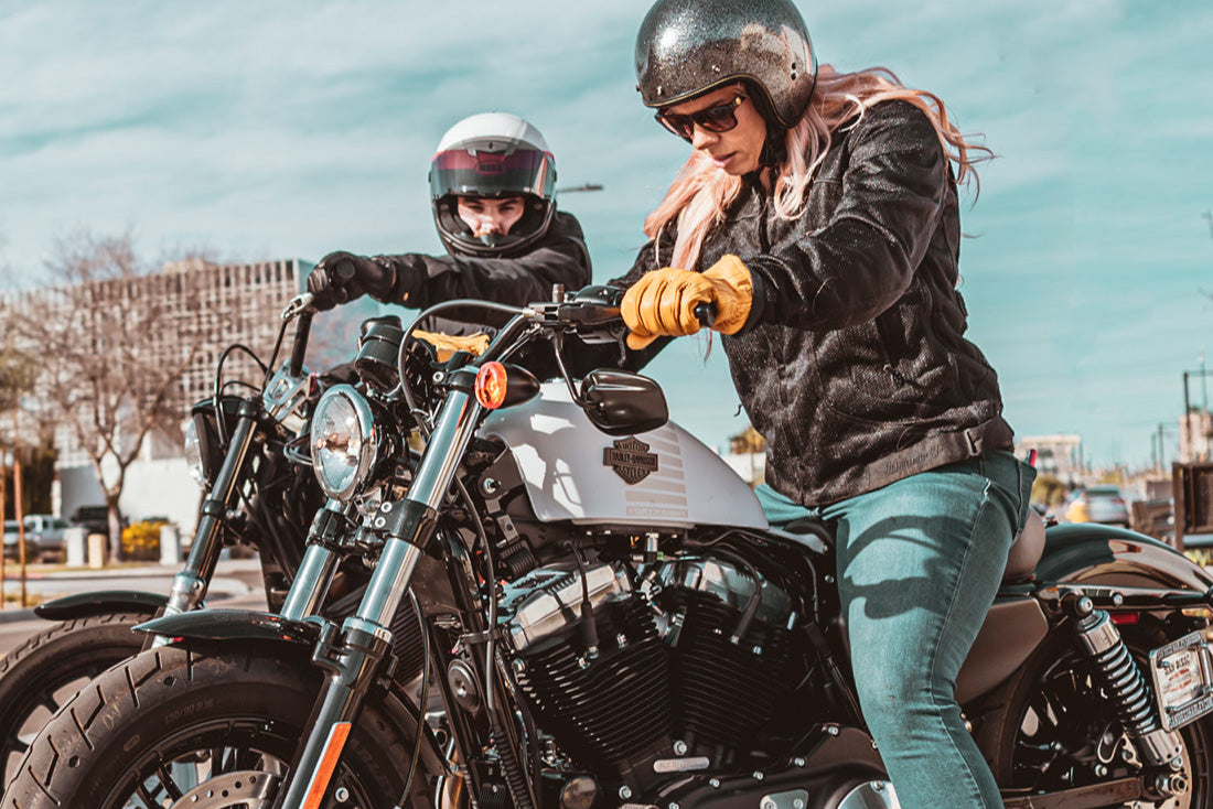 Two people on motorcycles with a clear sky background