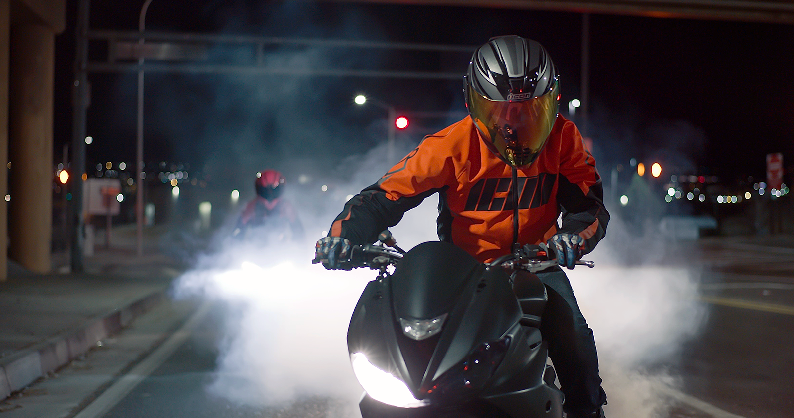 Person riding a motorcycle at night with bright lights on a city street.