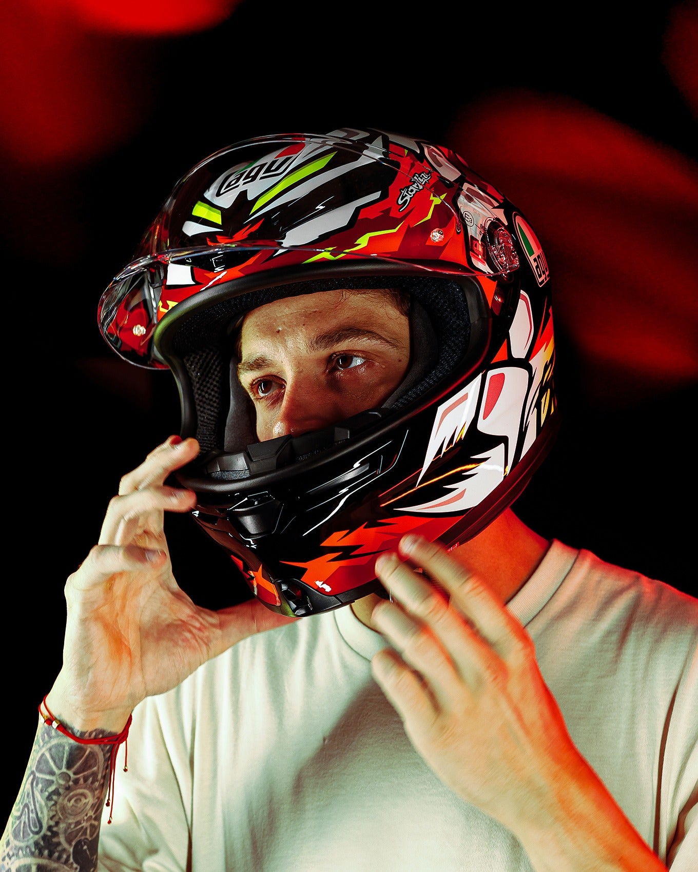 Person wearing a colorful motorcycle helmet with a red and black background