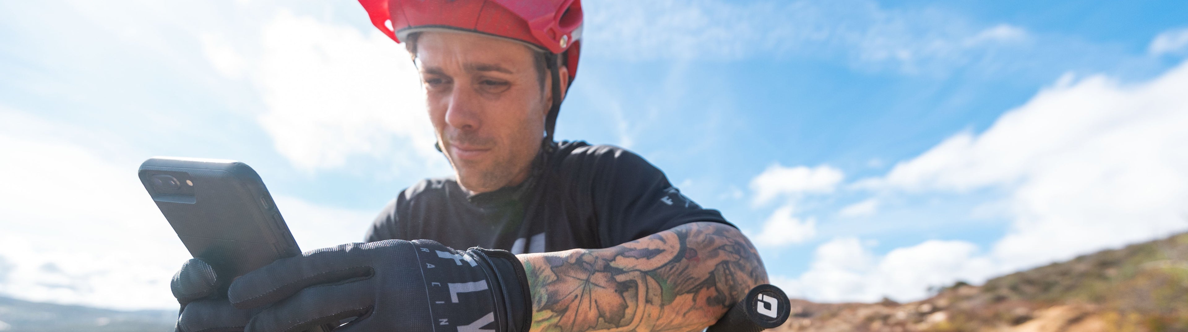Person on a mountain bike using a smartphone with a scenic background