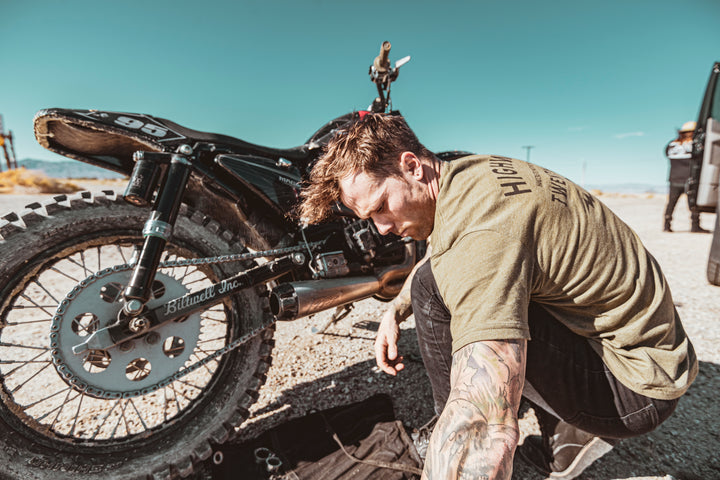 Man working on a motorcycle in a desert setting