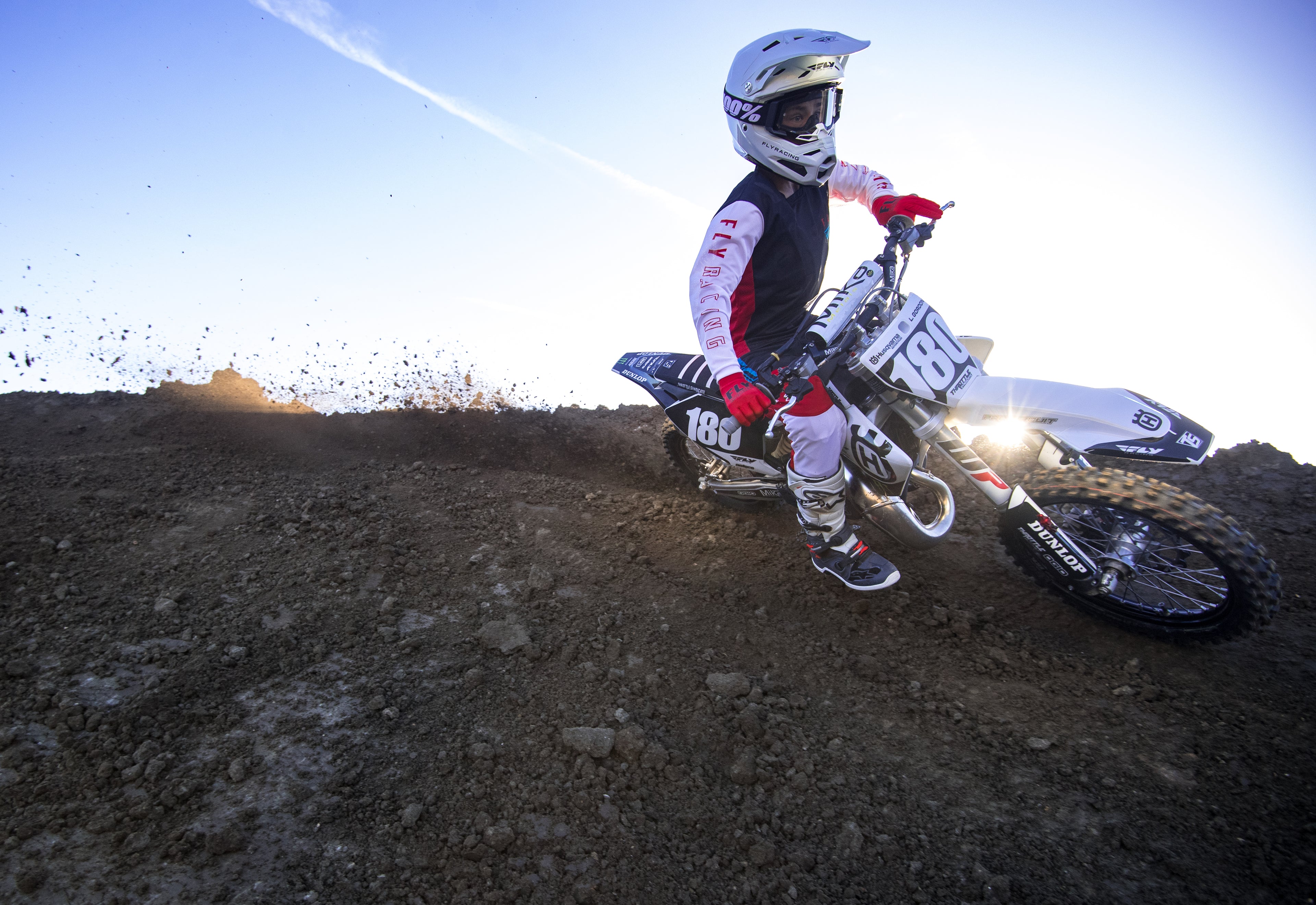 Motocross rider on a dirt bike on a track with a clear sky.