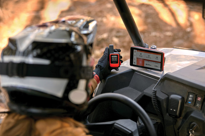 Person wearing a helmet using a GARMIN GPS device on a UTV dashboard.