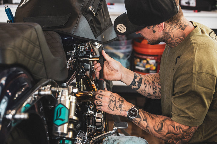 Man with tattoos working on a motorcycle engine