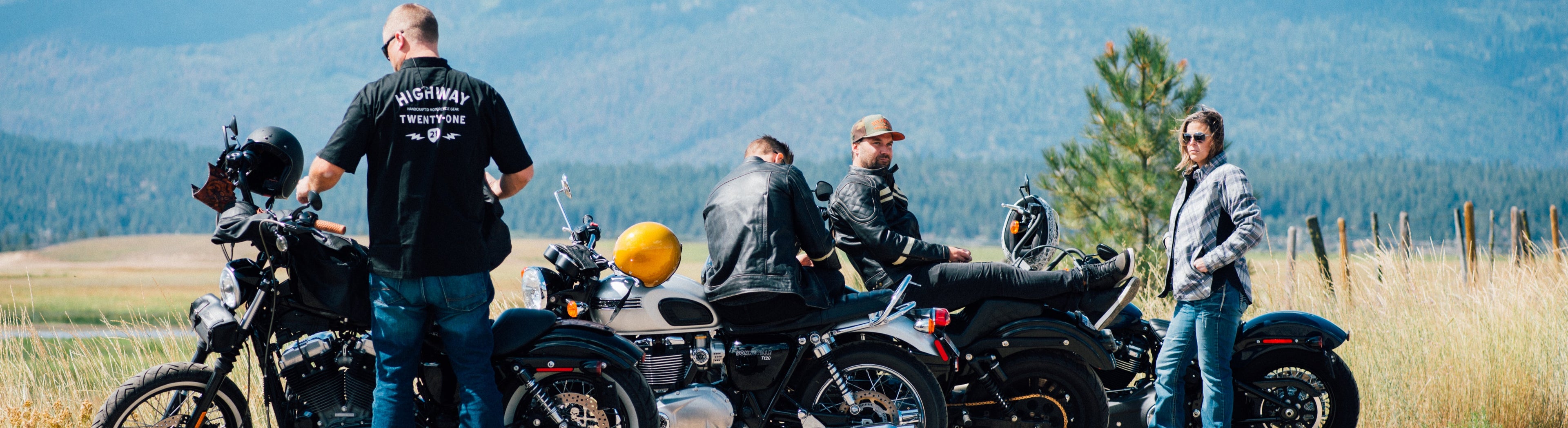 Group of people with motorcycles on a road with mountains in the background