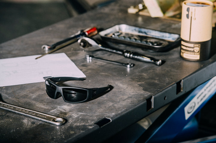 Sunglasses on a workbench with tools and a coffee cup in the background