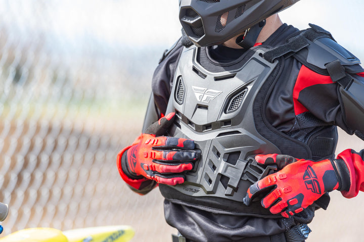 Person wearing a black and red motocross outfit with a helmet and gloves.