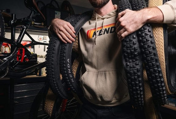 Person holding two bicycle tires with a brand logo on a blurred background